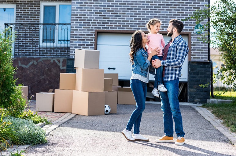 happy family of three outside their new place with boxes and a soccer ball