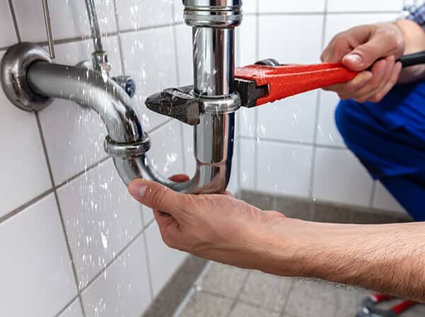 plumber working on leaking commercial sink