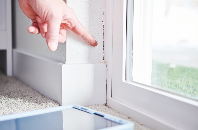 person pointing to crack in corner